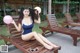 A woman in a blue bathing suit sitting on a wooden bench.