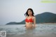 A woman in a red bikini standing in the water.