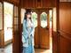 A woman in a blue kimono standing in front of a door.