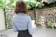 A woman in a blue shirt and black skirt writing on a clipboard.