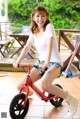 A woman riding a red balance bike on a tiled floor.