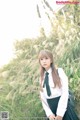 A woman in a school uniform standing in tall grass.