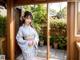 A woman in a blue kimono standing in front of a window.