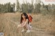 A woman crouching down in a field with a backpack.