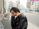 A woman in a black leather jacket standing on the side of a street.