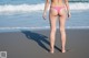 A woman in a pink bikini standing on a beach.