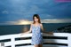 A woman in a blue and white dress standing on a balcony.