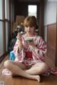 A woman in a kimono sitting on the floor eating a bowl of food.