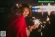 A woman in a red sweater holding a sparkler.