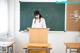 A woman standing at a podium in front of a blackboard.