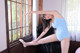 A woman in a blue leotard is posing by a window.